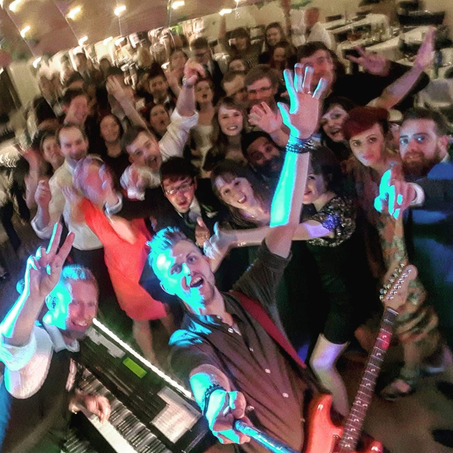 The Crazy Knights taking a selfie with a big crowd of people at a wedding.